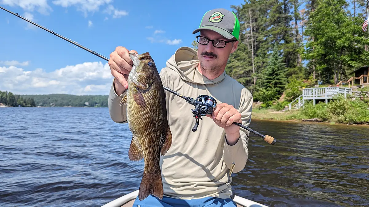 Hobie Wan Kenobi assis dans un bateau tenant un poisson avec une canne à pêche à l'aide du moulinet Daiwa Tatula BF TW 70 