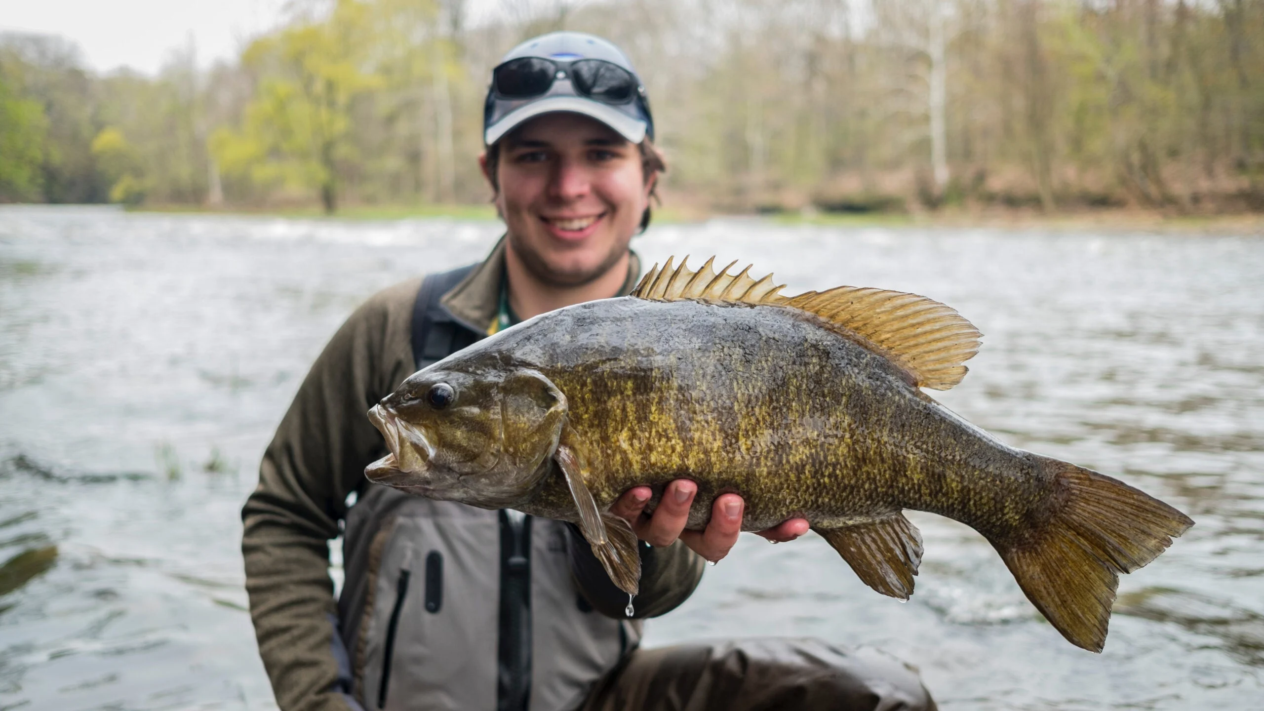 Pêcheur mâle tenant l'achigan à petite bouche sur la rivière à New York
