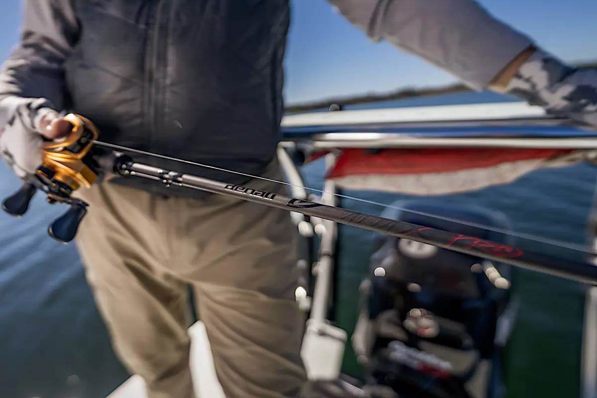Le pêcheur tient une canne à pêche et un moulinet.