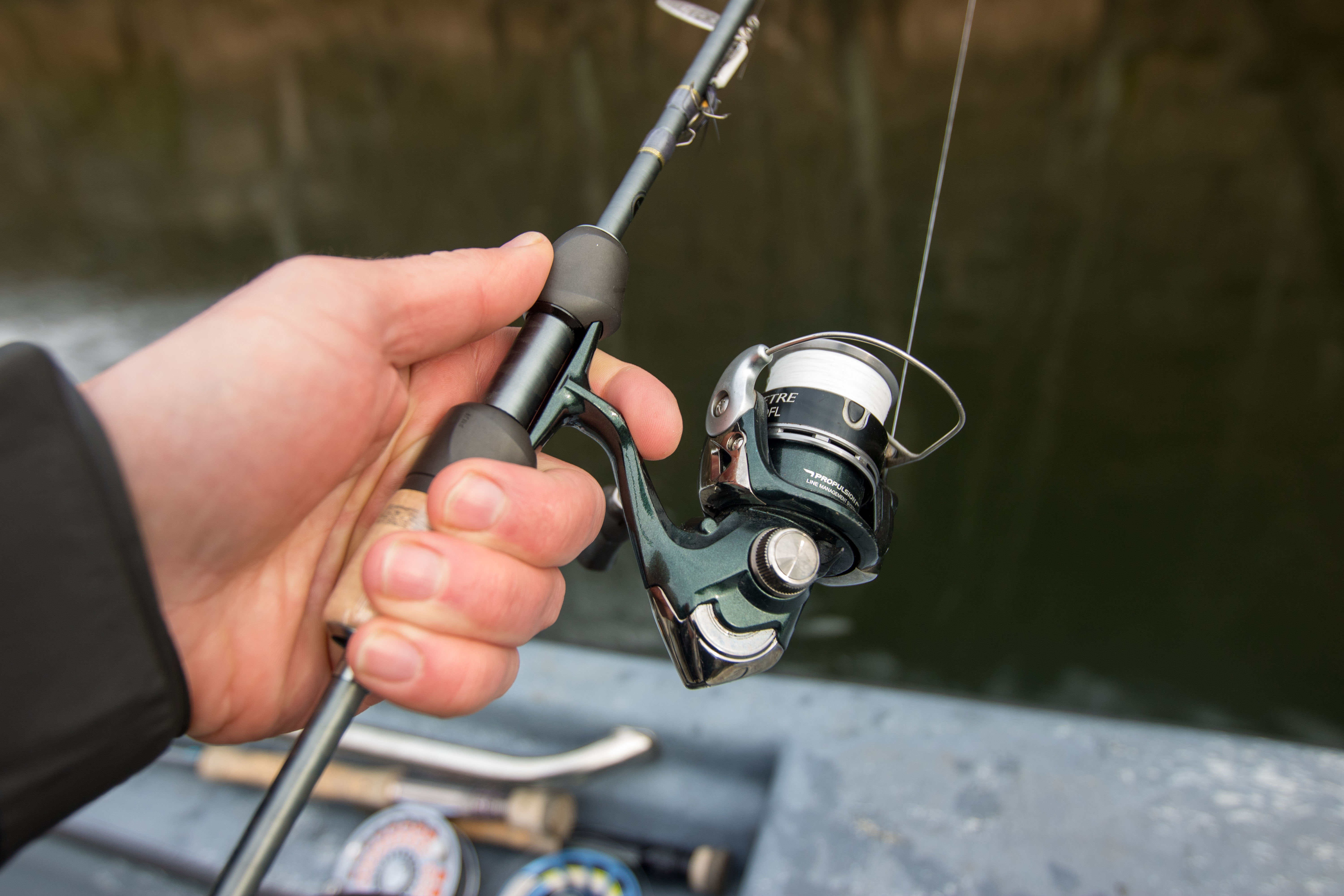 Un manche de canne à pêche dans la main du pêcheur.