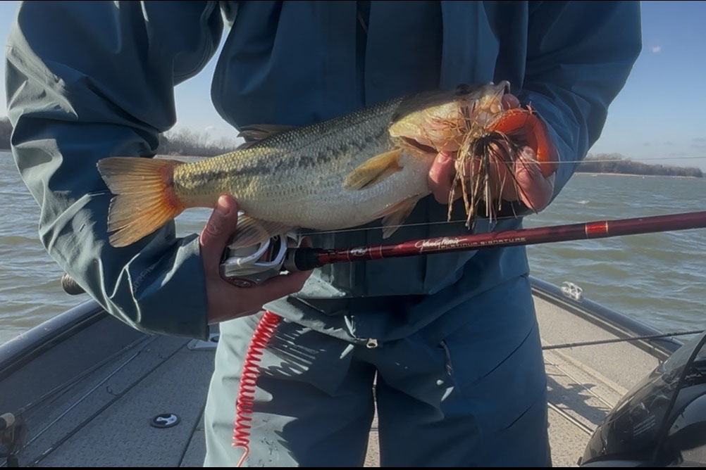 Un bar avec un gabarit dans la bouche à côté d'une canne à pêche rouge.