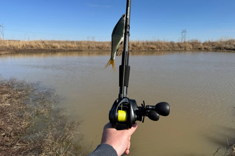 L'Abu Garcia Beast Baitcasting Combo est maintenu au-dessus d'un petit étang avec un leurre swimbait suspendu à la pointe de la canne.